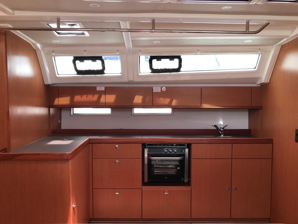 Een kleine keuken met inbouwapparatuur, een raam boven de gootsteen en een klein aanrecht.