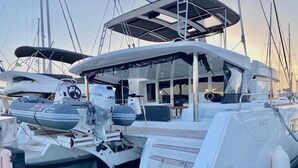 En småbåtshamn med en vit lyxyacht förtöjd vid bryggan. Yachten har ett täckt däck, ett ratt och en motor.