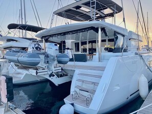 A marina with a white yacht docked, featuring a covered deck, a steering wheel, and a motor.