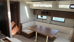 Een ruimtelijk bootinterieur met een eethoek, comfortabele zittingen en ramen met uitzicht op het water.