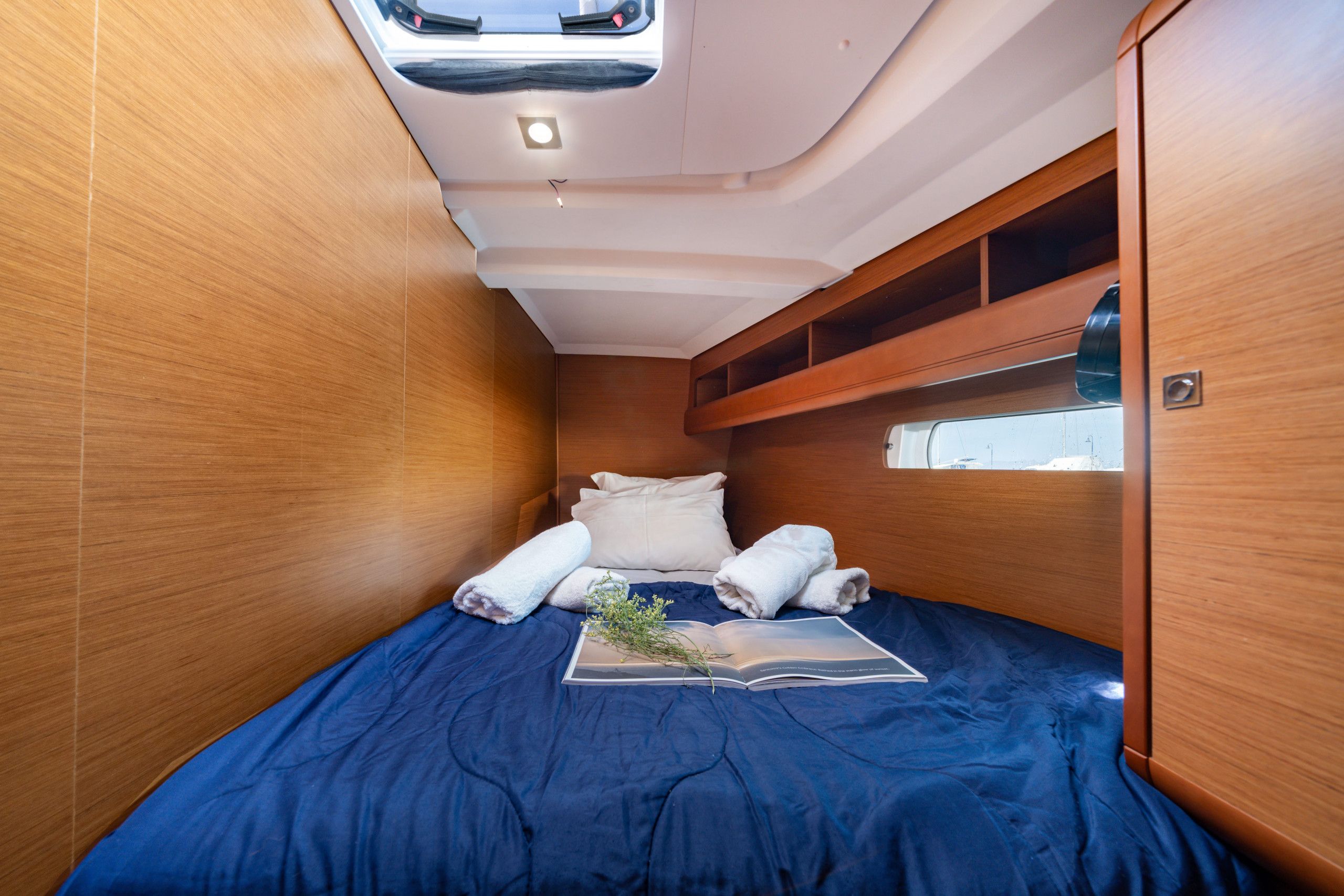Quarto compacto com cama, janela e prateleira embutida.