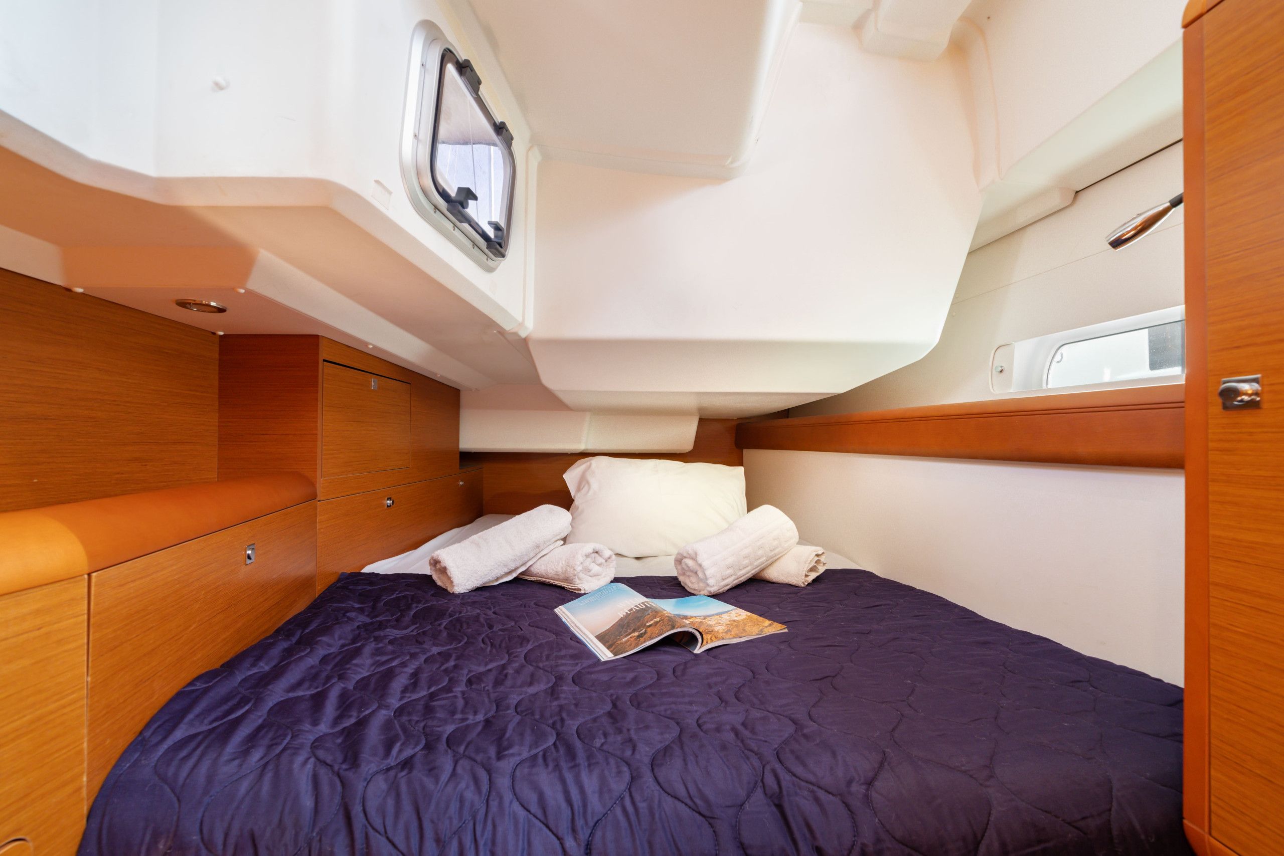 Une petite cabine comprenant un lit, une fenêtre et un petit espace de rangement.