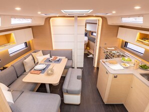 Ein kompaktes Wohnmobil-Interieur mit Essbereich, Küchenzeile und Sitzgelegenheiten.
