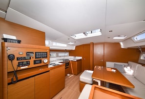 A compact galley with a stove, sink, and control panel, wooden cabinetry, and a small seating area with cushions. - Sun-Kissed Sailing Adventure in Zadar, Croatia (Bibinje)