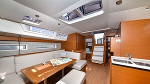 Une cuisine compacte avec un évier, un coin repas comprenant une table et des bancs, et un petit espace détente avec des coussins.