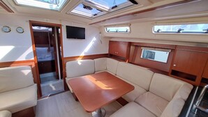 A compact interior with a central table, cushioned seating, a TV, and skylights. - Sun-Kissed Sailing Adventure in the Saronic Islands (Lavrio)