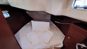 A small cabin with a bed, pillows, and a wooden cabinet. - Sun-Kissed Sailing Adventure in the Saronic Islands (Lavrio)