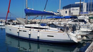 Eine Marina mit mehreren dort vertäuten Segelbooten, im Hintergrund ein Gebäude mit der Aufschrift 'LUKA BASKA VODA RESTAURANT' und ein klarer, blauer Himmel.