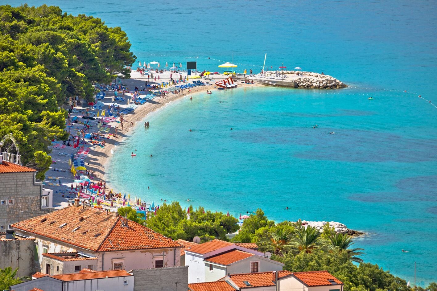 A coastal town with a beach, clear turquoise waters, and traditional architecture.