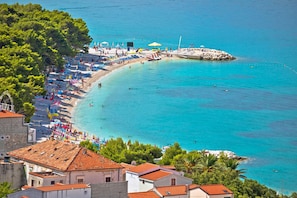 Eine Küstenstadt mit Strand, klarem türkisblauem Wasser und traditioneller Architektur.