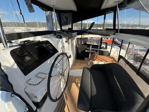 A boat's interior with a steering wheel, control panel, and seating area. - Sun-Kissed Sailing Adventure in Zadar, Croatia (Bibinje)