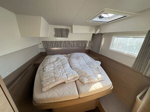 A compact bed with a headboard, a skylight, and a window with curtains. - Sun-Kissed Sailing Adventure in Zadar, Croatia (Bibinje)