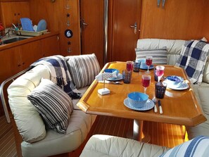 Ein Essbereich mit Holztisch, weiß gepolsterten Sitzgelegenheiten und maritimer Dekoration.