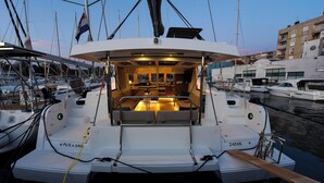 A boat with a covered deck area, a seating arrangement, and a view of the marina with other boats. - Sun-Kissed Sailing Adventure in Zadar, Croatia (Zadar)