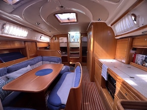 Un intérieur de camping-car compact comprenant un coin repas, des sièges et une petite kitchenette.