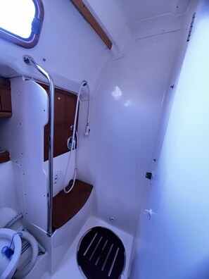A compact bathroom with a shower, toilet, and sink.