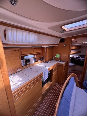 A compact galley with wooden cabinetry, a sink, and a small window.