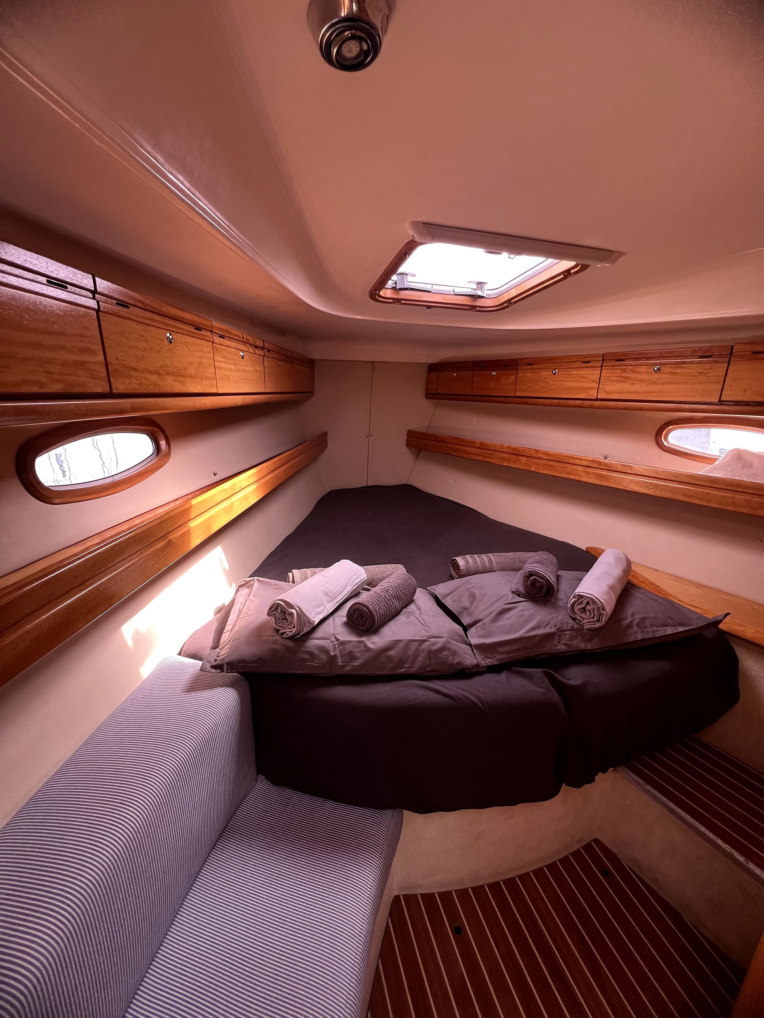 Une petite cabine comprenant un lit, une tête de lit en bois et des rangements intégrés.