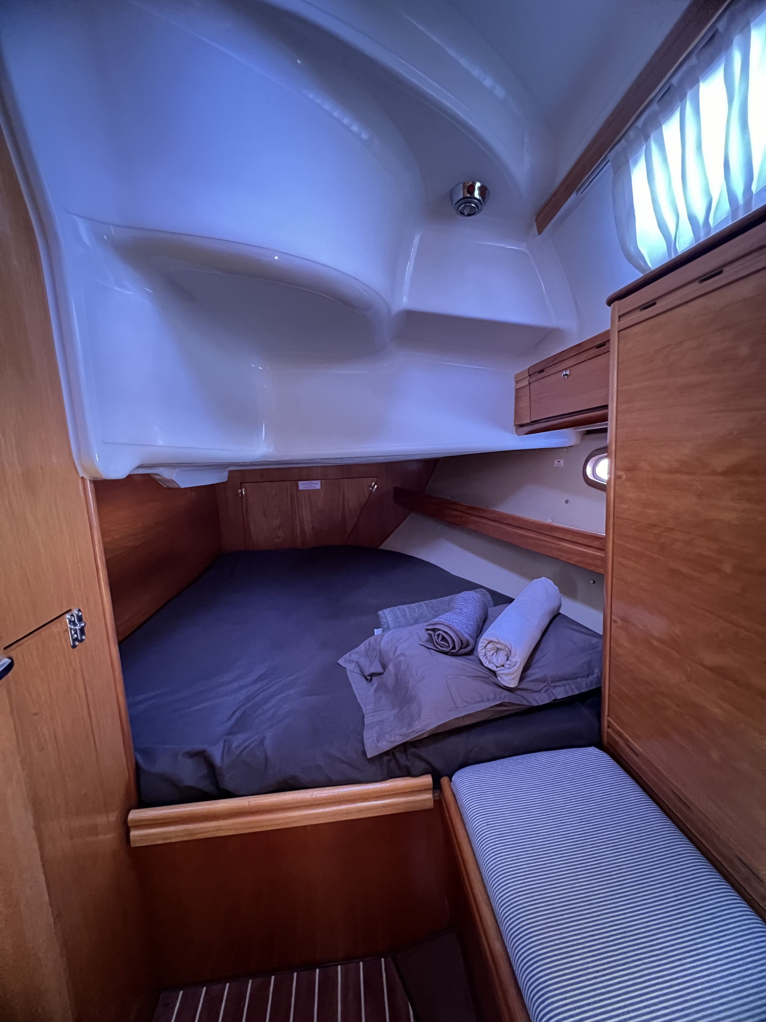 Une cabine compacte comprenant un lit superposé, un petit coin salon et une fenêtre avec des rideaux.