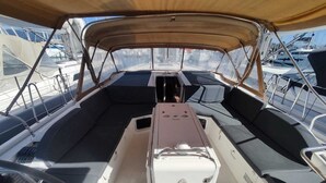 L'intérieur d'un bateau, avec une console centrale, des sièges rembourrés et des barrières en métal.