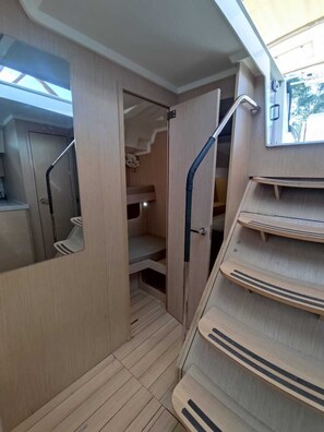 A compact, multi-level wooden interior with a mirrored wall, a staircase, and a small storage area. - Sun-Kissed Sailing Adventure in the Ionian Islands, Lefkada (Lefkada)