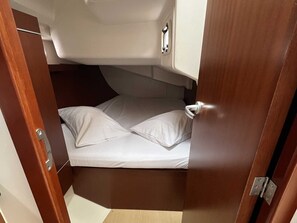 Een bescheiden, afgesloten slaapgedeelte met een bed, kussens en een deur.