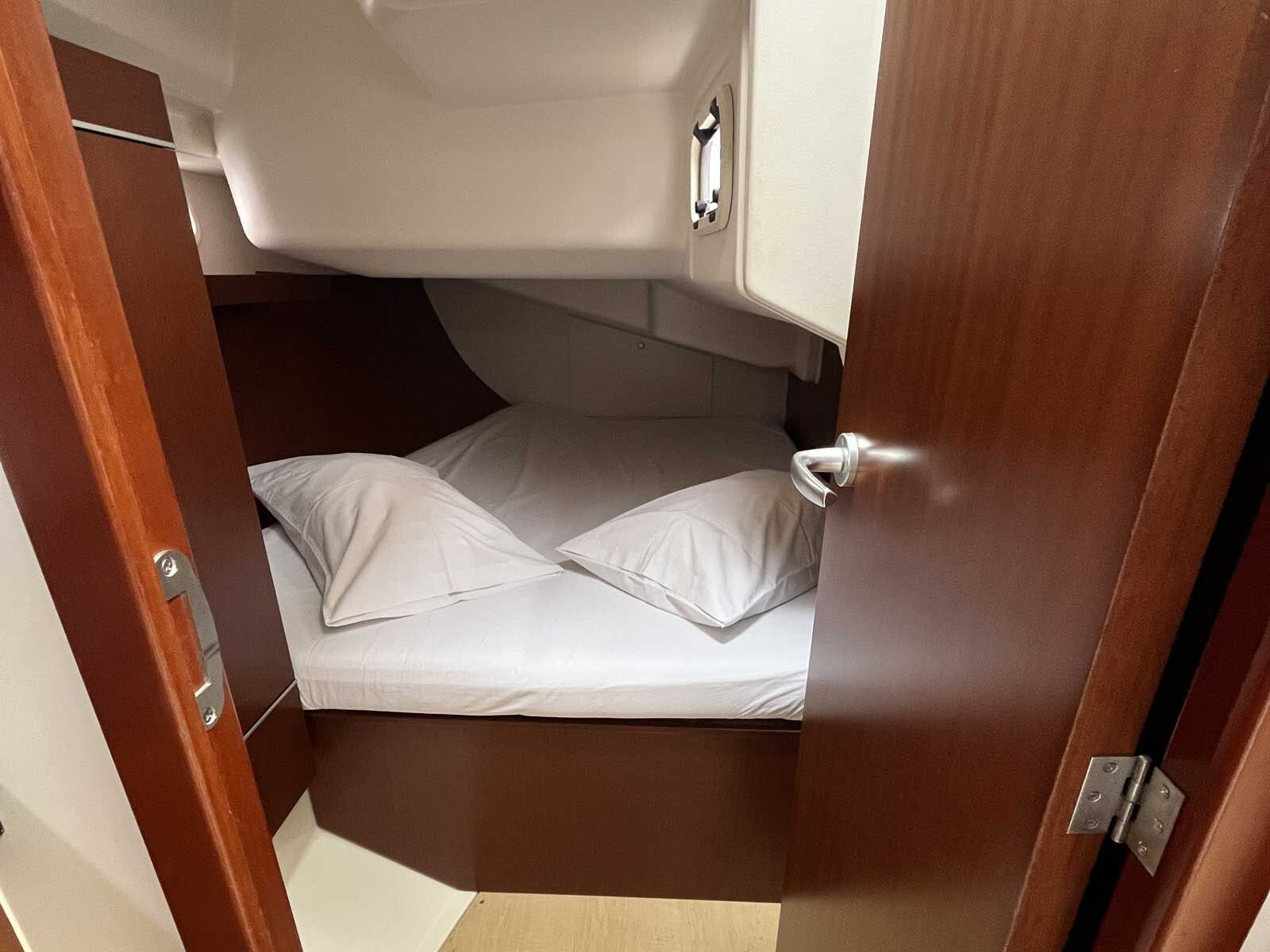 A compact, enclosed sleeping area with a bed, pillows, and a door.