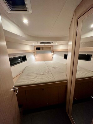 Ein gemütliches, gut beleuchtetes Kabinenzimmer mit einem Bett, Stauraum und einer kleinen Sitzecke.