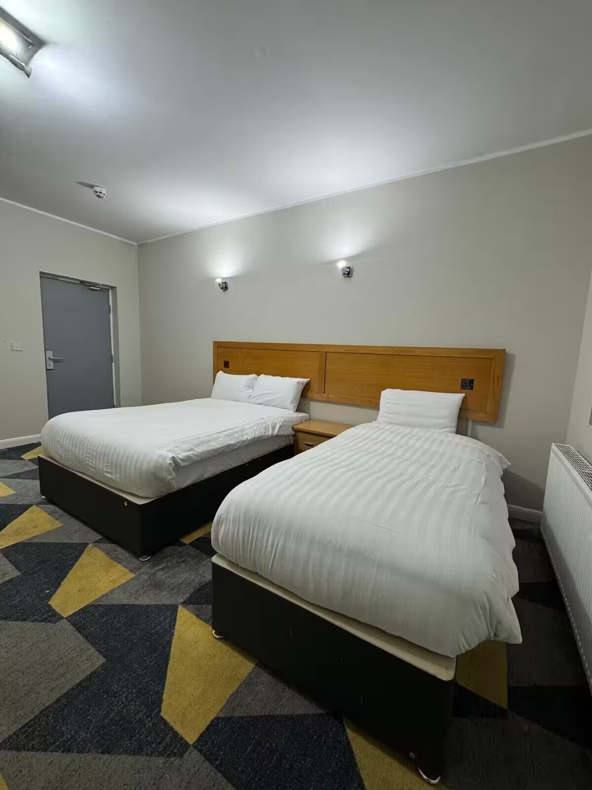 Habitación de hotel con dos camas, una puerta y un radiador.