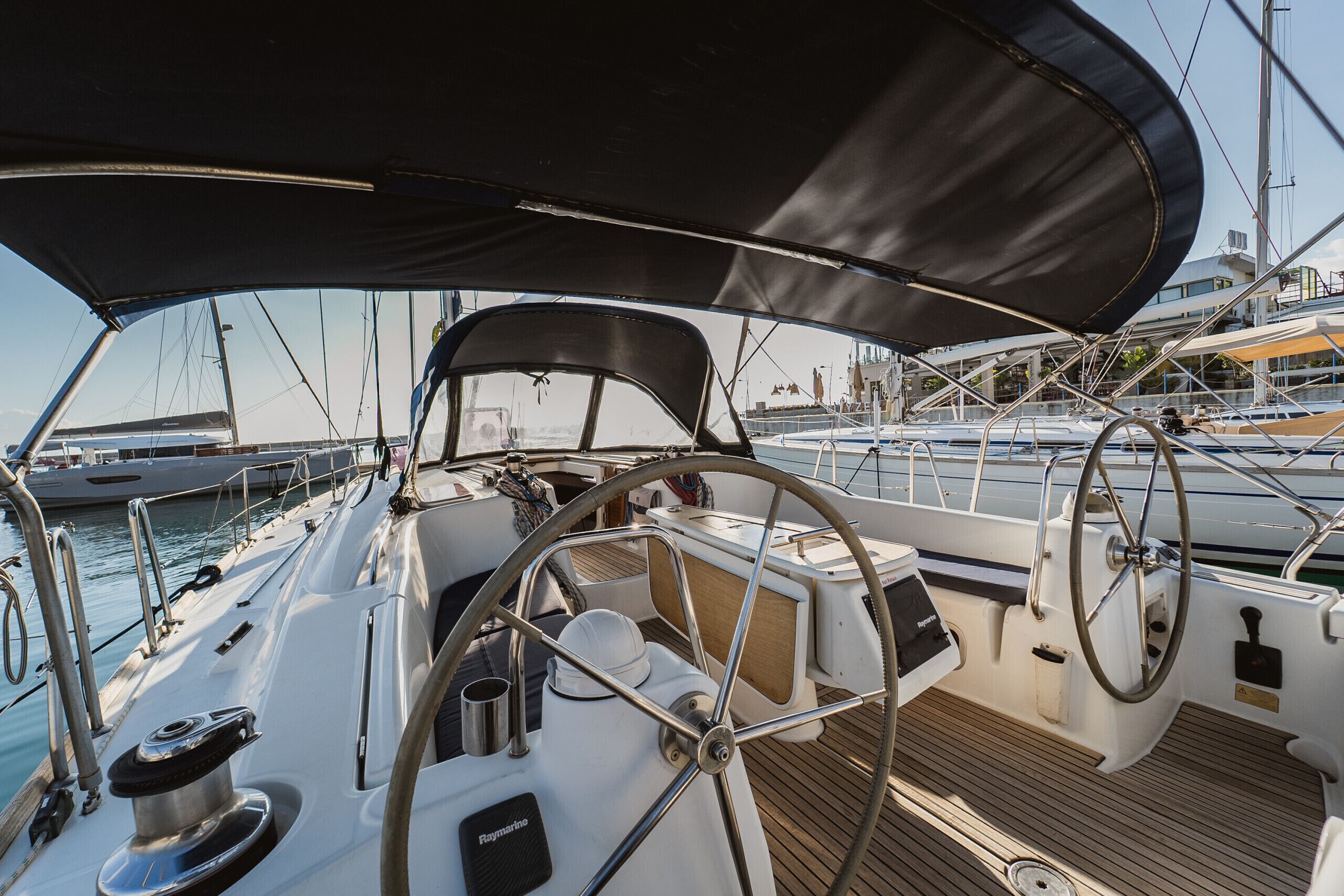 A sailboat deck with a steering wheel, a winch, and a small table.