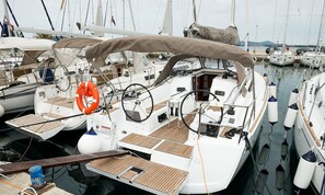A marina with multiple sailboats docked, featuring wooden deck areas, steering wheels, and life rings. - Sibenik Sun-soaked Sailing: A Luxurious Croatian Voyage (Pirovac)