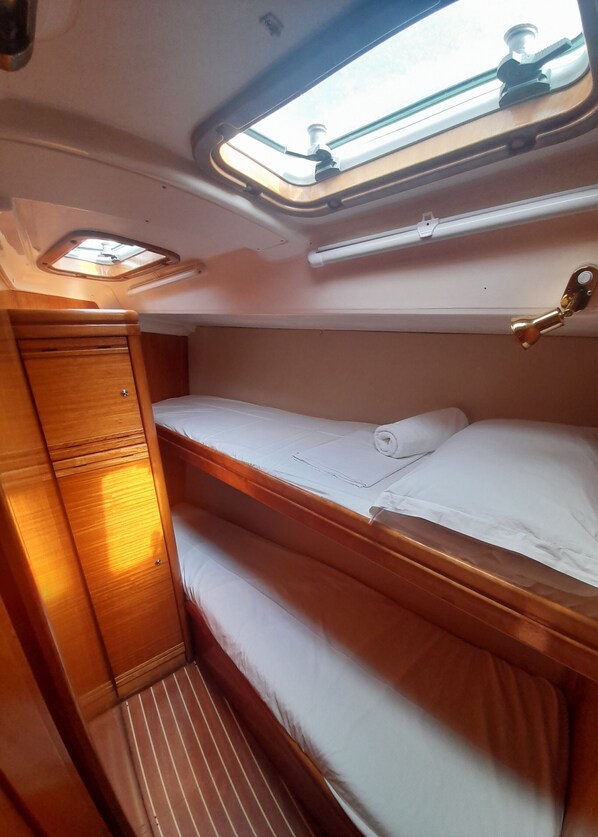 Une cabine compacte équipée d’un lit superposé, d’une petite armoire et d’un puits de lumière.