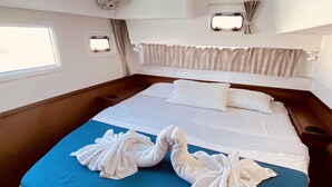 A bed with a blue mattress, white linens, and towels arranged in a heart shape. - Sun-Kissed Sailing Adventure in the Ionian Islands, Lefkada (Lefkada)