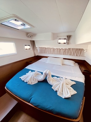 Ein Bett mit blauer Matratze, weißen Textilien und Handtüchern, die zu einem Herz geformt sind.