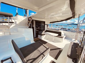 A boat's interior with seating areas, a table, and a view of the marina. - Sun-Kissed Sailing Adventure in the Ionian Islands, Lefkada (Lefkada)
