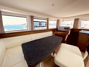 A cabin with a table, a chair, a control panel, and windows with a view of the sea. - Sun-Kissed Sailing Adventure in the Ionian Islands, Lefkada (Lefkada)