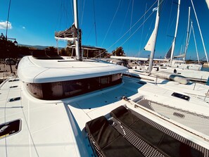 A marina with multiple sailboats docked, featuring a covered deck area with seating and a large window. - Sun-Kissed Sailing Adventure in the Ionian Islands, Lefkada (Lefkada)