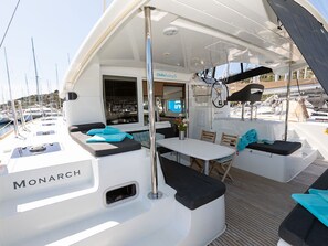 A boat named 'Monarch' with a dining area, seating, and a view of the marina. - Sun-Kissed Sailing Adventure in Sibenik, Croatia (Primošten)