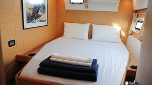 A neatly made bed with pillows, a small window with curtains, and a framed picture on the wall. - Sun-Kissed Sailing Adventure in the Sporades Islands from Volos, Thessaly (Volos)