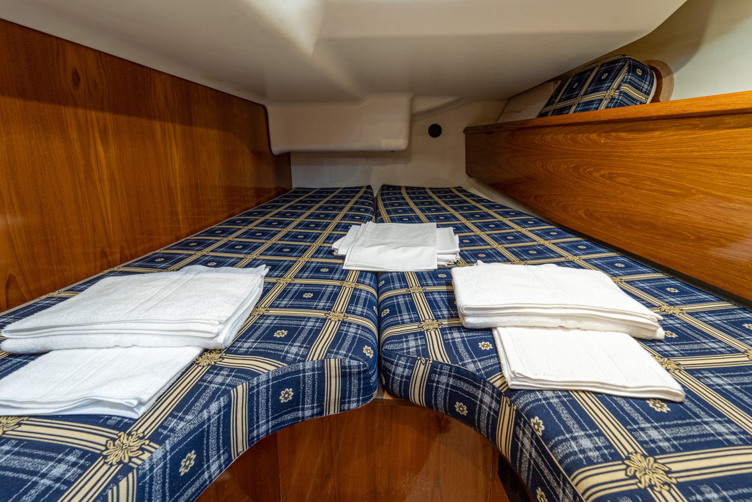 Een compact bed met een beddegoed met patroon en keurig opgevouwen witte handdoeken.