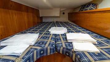 Een compact bed met een beddegoed met patroon en keurig opgevouwen witte handdoeken.