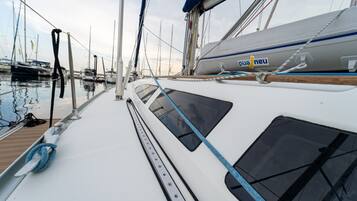 Un port de plaisance où sont amarrés plusieurs voiliers, avec une cabine blanche dotée de fenêtres et d’une corde bleue.