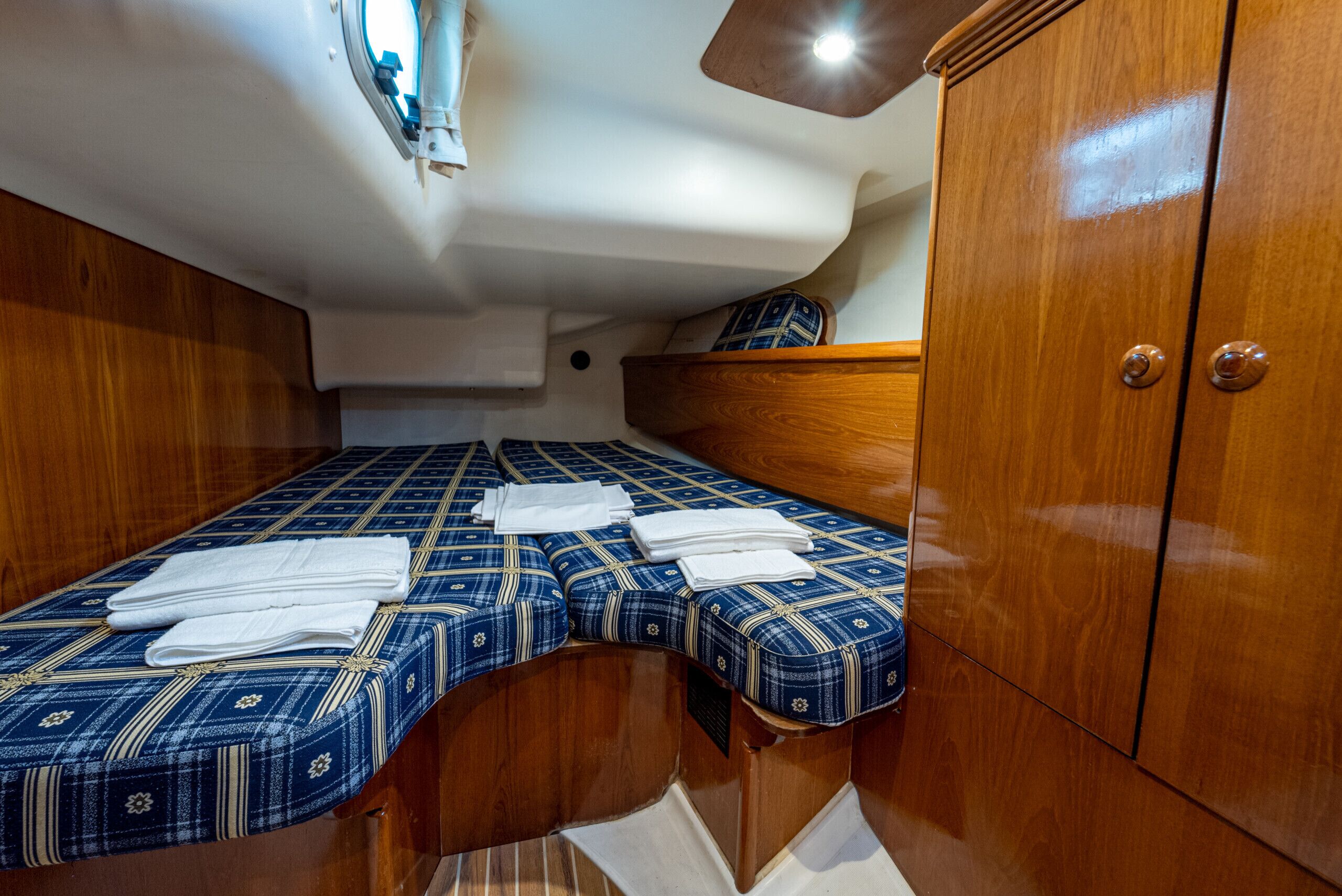 A compact cabin with a bed, wooden wardrobe, and a small window.