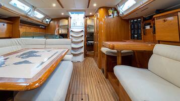 L’intérieur d’un bateau, comprenant un coin repas, des sièges et un panneau de commande.