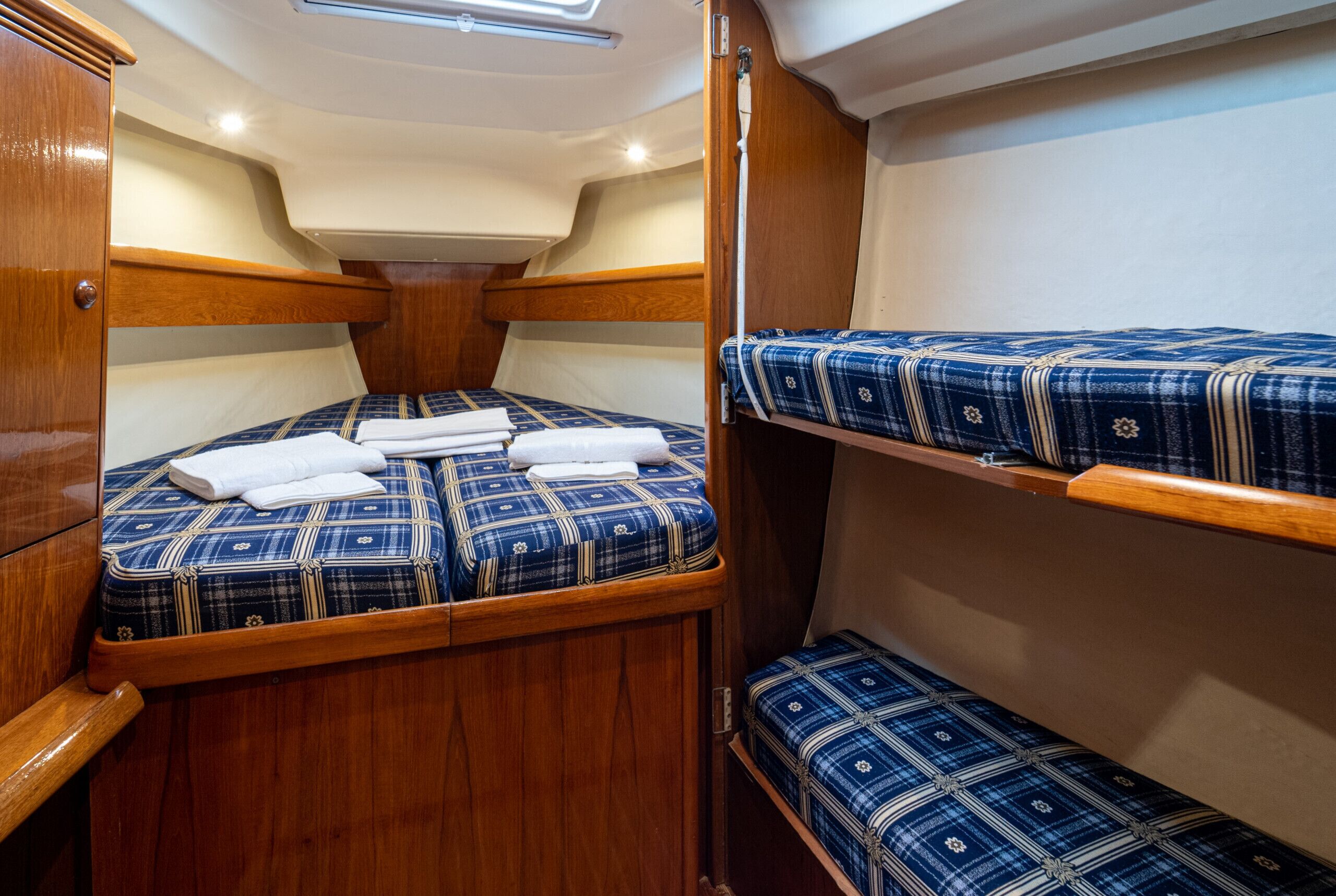 A compact cabin with two bunk beds, wooden trim, and a small overhead light.