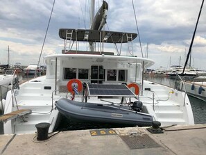 Ein Boot liegt an einem Hafensteg, an dem ein kleines Schlauchboot befestigt ist. Ein Rettungsring ist ebenfalls vorhanden, und auf dem Steg ist die Nummer '256' zu sehen.