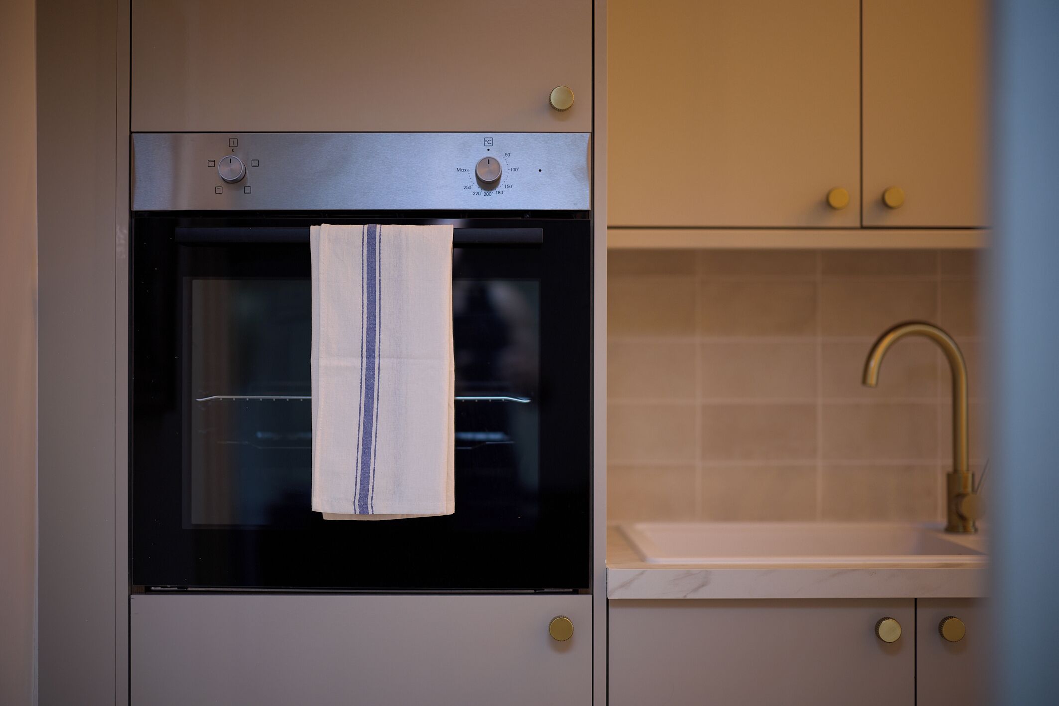 Eine K üche mit Backofen, Spüle und einem Handtuch, das an der Backofentür hängt.