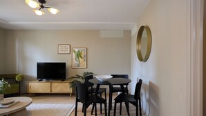 A living room with a TV, dining table, chairs, a sofa, and a mirror. - The Westbourne Side Story (London)