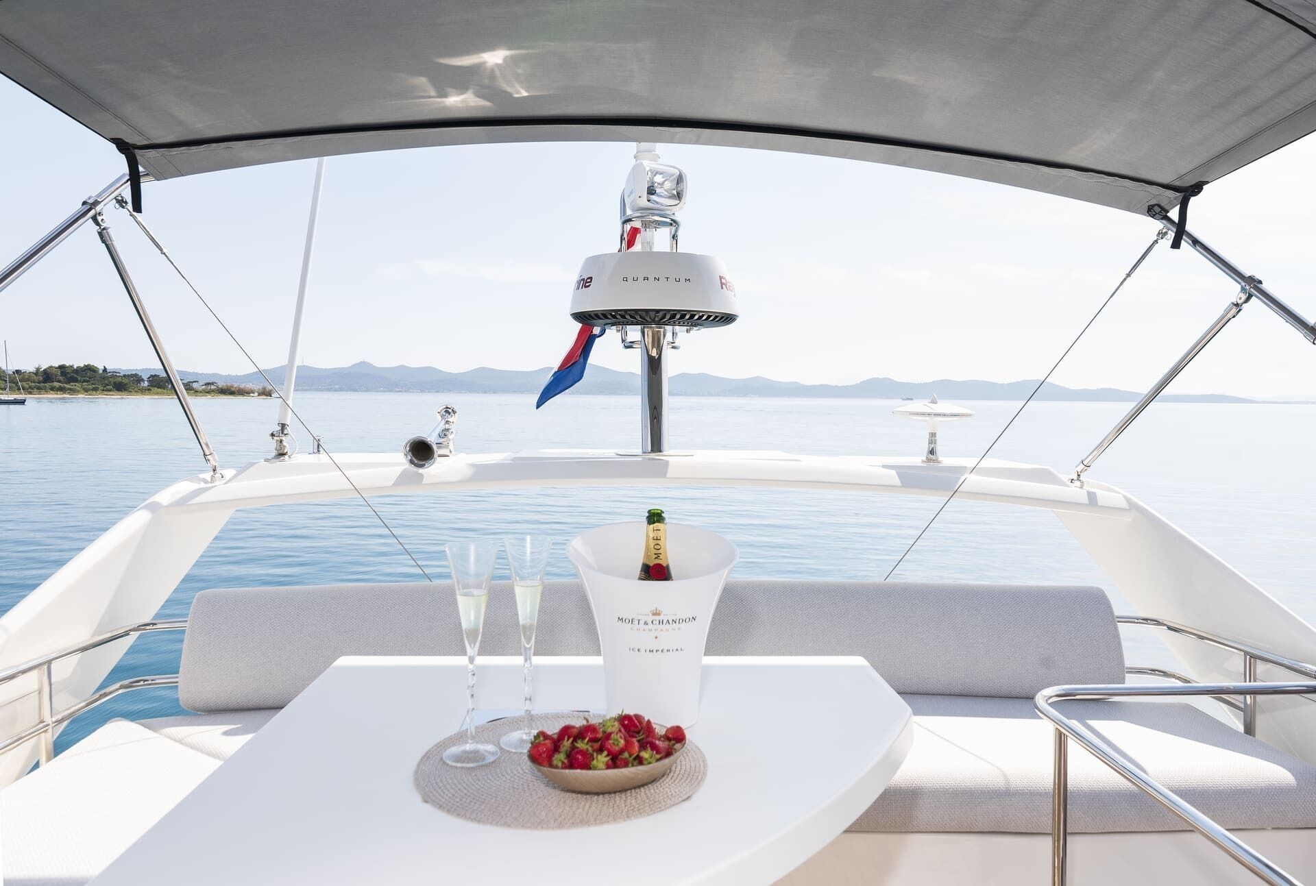 A boat with a table set for two, a bottle of champagne, and a bowl of strawberries.