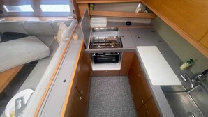 A compact kitchenette with a stove, sink, and storage cabinets. - Sun-Kissed Sailing Adventure in Islas Cícladas, Mykonos (Mykonos)